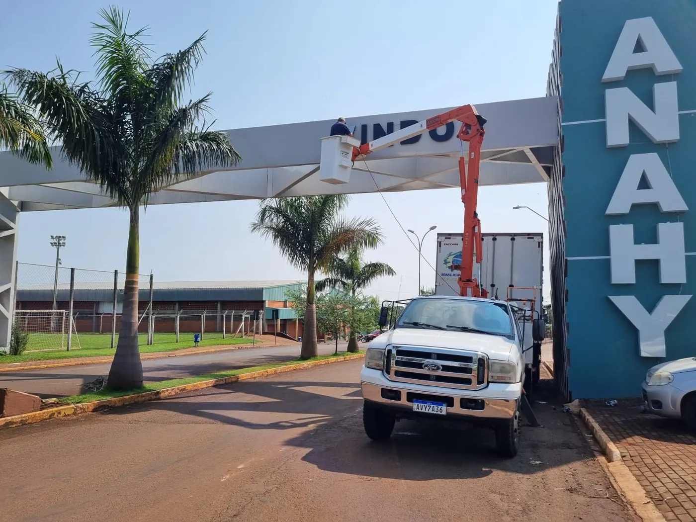 Ford F-4000 com cesto aéreo instalando letras no pórtico de entrada de Anahy-PR